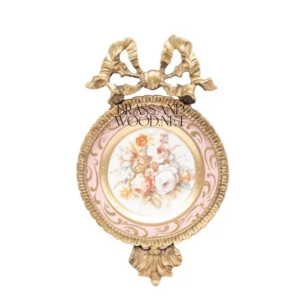 Antique brass wall art with ribbon top ornate frame and pink floral porcelain centerpiece in classic vintage design